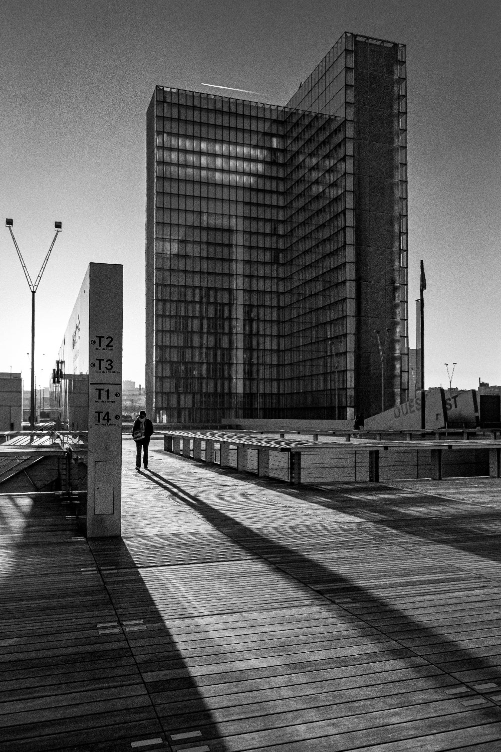 Photographie noir et blanc de la Bibliothèque nationale de France à Paris avec longues ombres au coucher du soleil sur le parvis