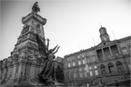 Photo en noir et blanc de la statue d’Infante D. Henrique à Porto, cadrage serré et perspective forte, avec le Palais Da Bolsa en arrière-plan.