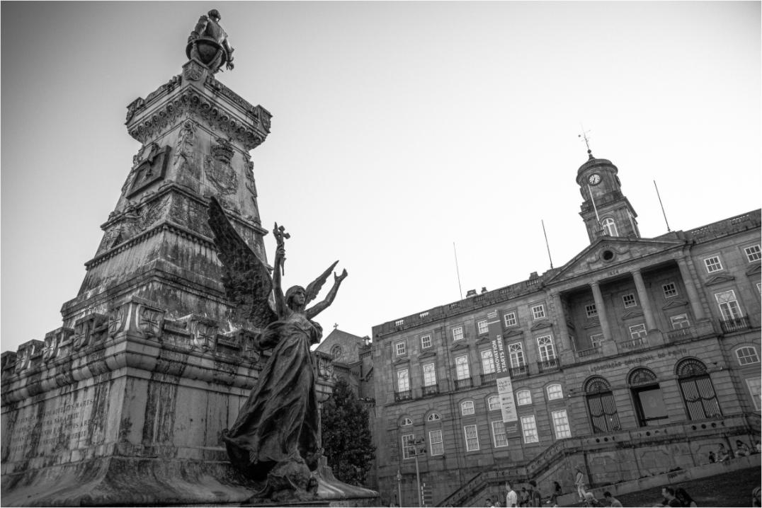 Photo en noir et blanc de la statue d’Infante D. Henrique à Porto, cadrage serré et perspective forte, avec le Palais Da Bolsa en arrière-plan.