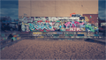 Tirage photo JOE à Berlin avec mur de graffitis variés entre la Spree et East Side Gallery, ambiance urbaine vintage aux couleurs éclatantes.