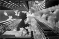 Photo en noir et blanc de quatre gratte-ciels de New York, prise en contre-plongée avec un ciel nuageux, perspective graphique et spectaculaire.