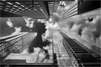 Photo en noir et blanc de quatre gratte-ciels de New York, prise en contre-plongée avec un ciel nuageux, perspective graphique et spectaculaire.