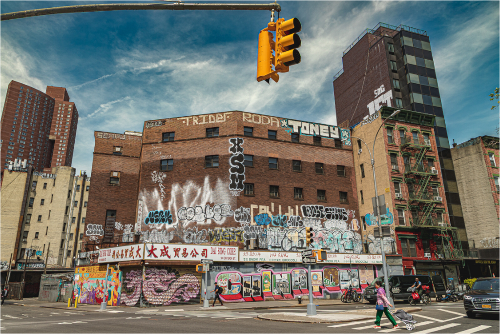 Photo d’un bâtiment à Chinatown, New York, couvert de graffitis avec la fresque "Greetings from Chinatown", scène urbaine et artistique.