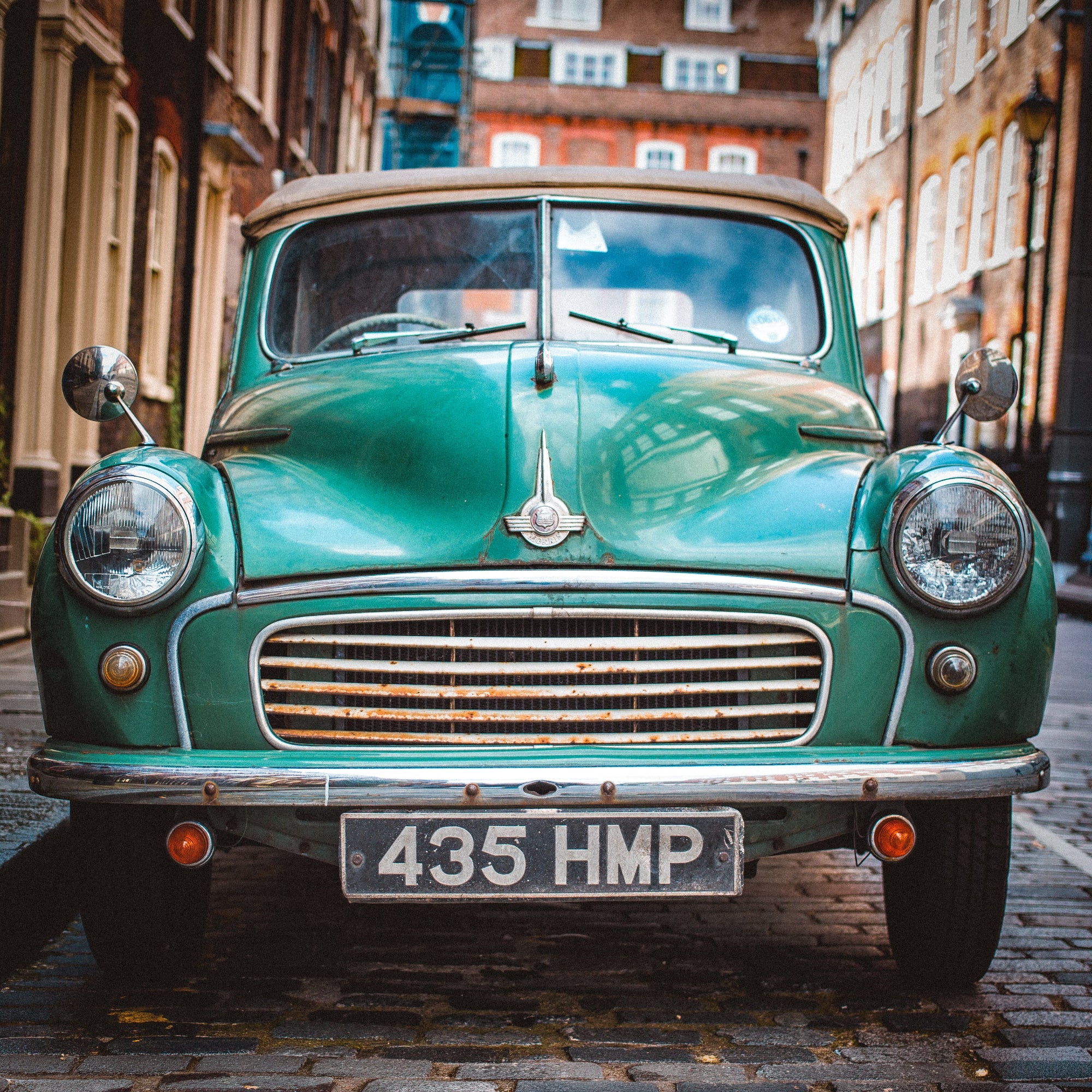 Plonge dans l’atmosphère authentique des rues pavées de&nbsp;Londres avec The Old Morris. Cette photographie capture de face une iconique Morris Minor 1000 Tourer verte, stationnée comme hors du temps.