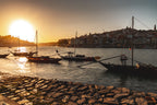 Photo du port de Porto au coucher du soleil avec bateaux traditionnels au premier plan et ville en arrière-plan dans une lumière chaude estivale